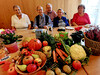 Caritas-Mitarbeiter Olaf Heiduk (hinten) feierte mit Teilnehmer*innen unserer CARENA-Gruppe das Erntedankfest. Die Lebensmittel auf dem Tisch vor ihnen gehen als Spende an den sozialen Mittagstisch des Guten Hirten.