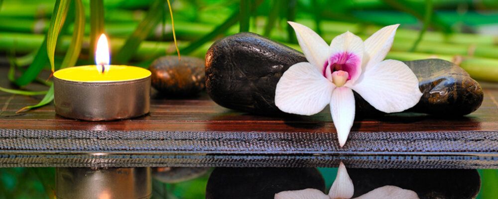 Wellness-Set mit Orchideenblüte, Kieselsteinen und Teelicht