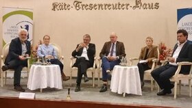 Menschen sitzen an Tischen auf einer Bühne