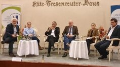 Menschen sitzen an Tischen auf einer Bühne