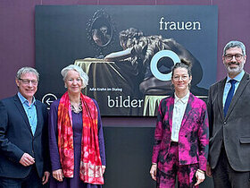 Künstlerin und drei weitere Personen vor dem Ausstellungsplakat