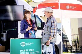 Frau spricht mit älterem Mann am Messestand